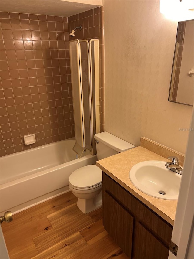 full bath with toilet, bathtub / shower combination, wood finished floors, and vanity