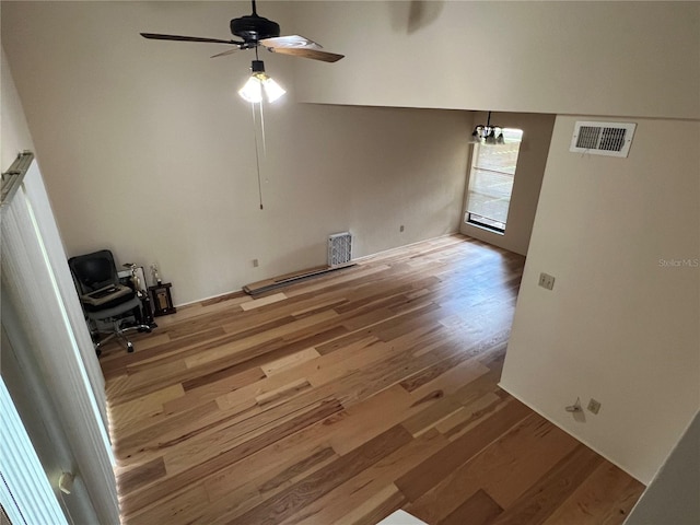 empty room featuring visible vents, ceiling fan, a towering ceiling, and wood finished floors