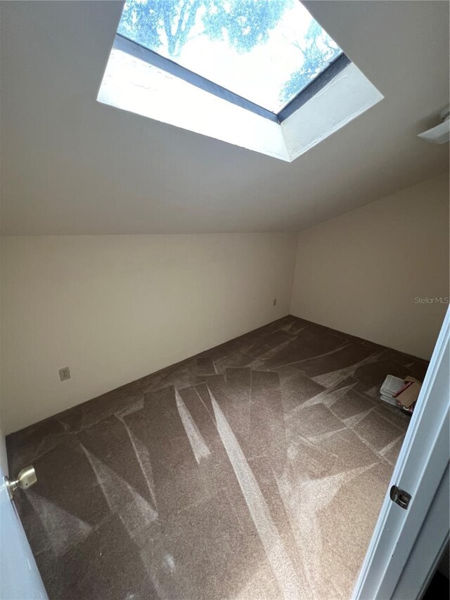 additional living space featuring carpet flooring and lofted ceiling with skylight