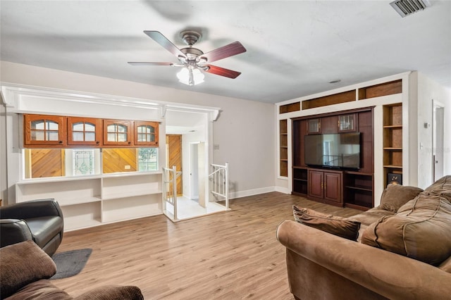 living room with ceiling fan, light hardwood / wood-style floors, and built in shelves