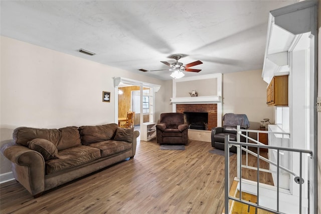 living room with hardwood / wood-style floors, ceiling fan, and a fireplace