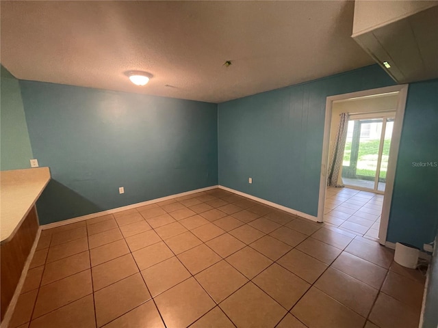 spare room with a textured ceiling and tile patterned floors