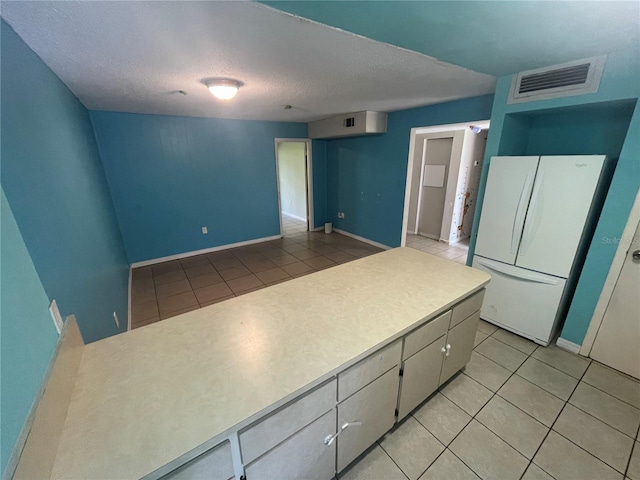 kitchen featuring a textured ceiling, white refrigerator, and light tile patterned floors