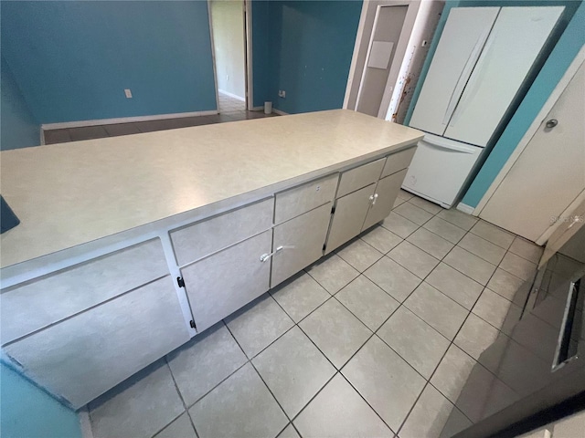 kitchen with white cabinets, light tile patterned floors, and white refrigerator