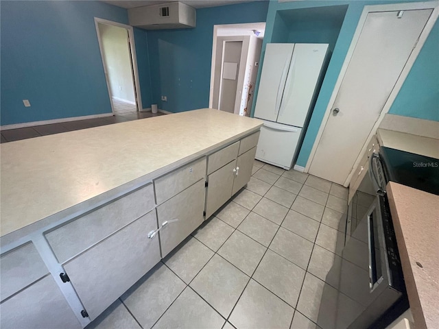 kitchen with light tile patterned flooring, white fridge, and stove