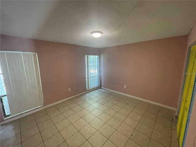 unfurnished room with a textured ceiling and light tile patterned floors