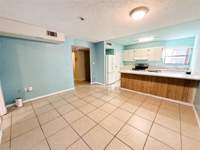 kitchen featuring sink, light tile patterned floors, kitchen peninsula, white fridge, and electric stove