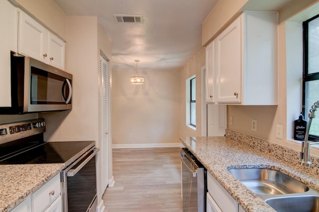 kitchen with appliances with stainless steel finishes, light stone counters, and white cabinetry