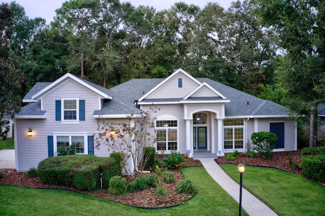 view of front facade with a front lawn and roof with shingles