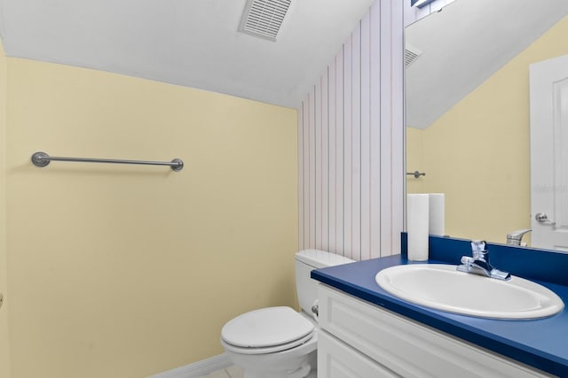 bathroom featuring vanity, toilet, and vaulted ceiling