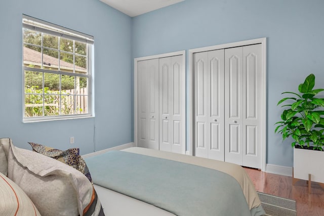 bedroom featuring hardwood / wood-style floors and multiple closets