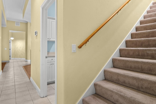 staircase with ornamental molding and tile patterned floors