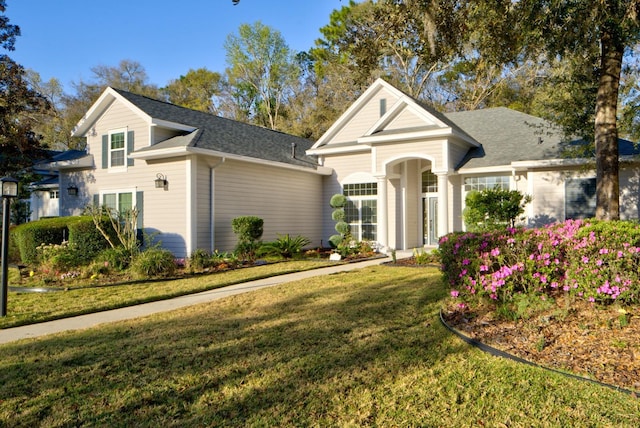 traditional-style house featuring a front lawn and a shingled roof