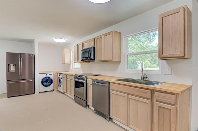 kitchen with appliances with stainless steel finishes, light brown cabinetry, sink, and washer and dryer