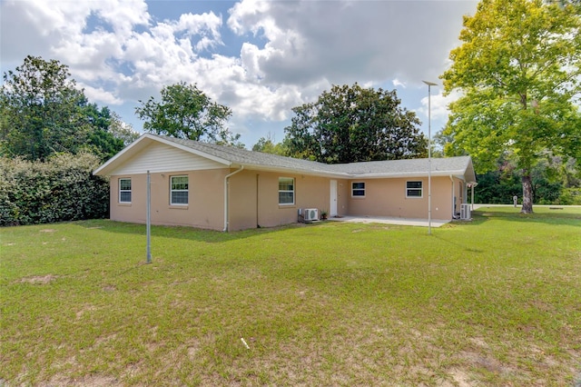 rear view of property with a lawn, cooling unit, and a patio area