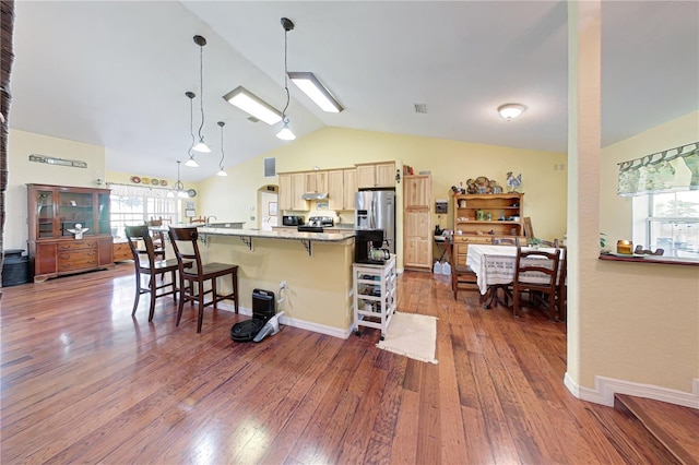 kitchen featuring plenty of natural light, vaulted ceiling, dark wood-type flooring, and a breakfast bar