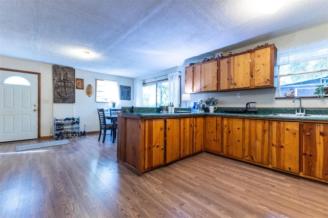 kitchen with sink, kitchen peninsula, a textured ceiling, and hardwood / wood-style floors