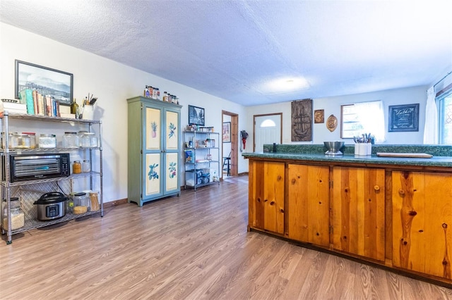 kitchen with hardwood / wood-style flooring, kitchen peninsula, and a textured ceiling