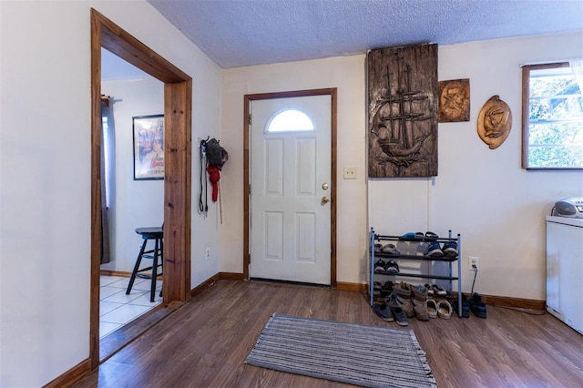 foyer with a textured ceiling, washer / dryer, and hardwood / wood-style flooring