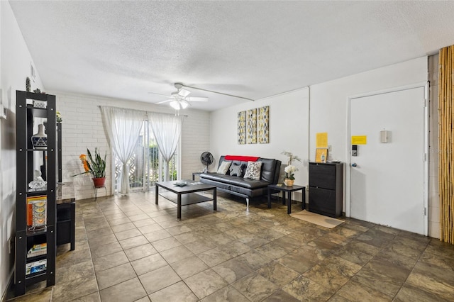 living room featuring ceiling fan, a textured ceiling, and tile patterned flooring