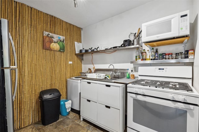 kitchen with wooden walls, white cabinetry, dark tile patterned floors, and white appliances