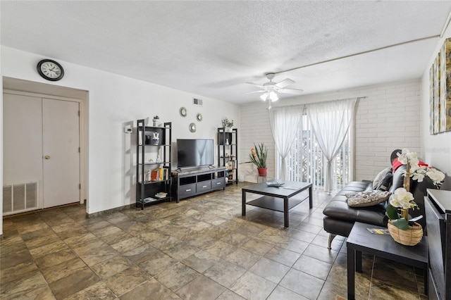 tiled living room with ceiling fan and a textured ceiling