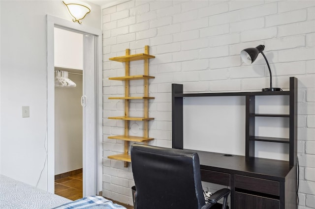 office with tile patterned floors and brick wall