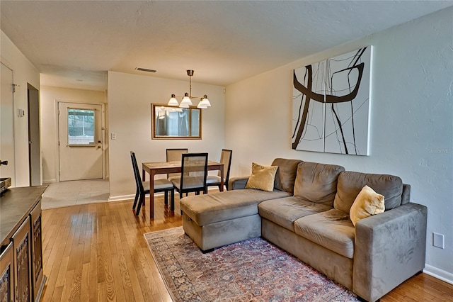 living room featuring light wood-type flooring and a notable chandelier