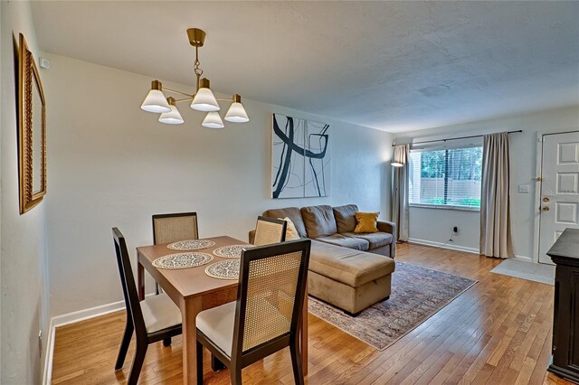 dining space featuring light hardwood / wood-style floors and an inviting chandelier