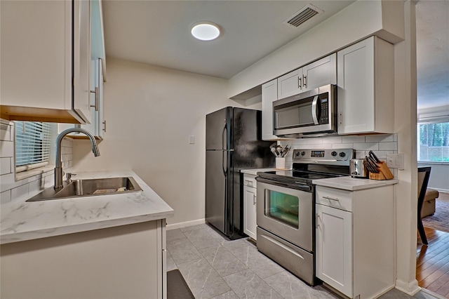 kitchen with white cabinets, stainless steel appliances, light tile patterned flooring, and sink