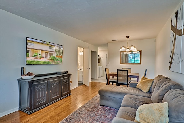 living room featuring a chandelier, washing machine and dryer, and light hardwood / wood-style flooring