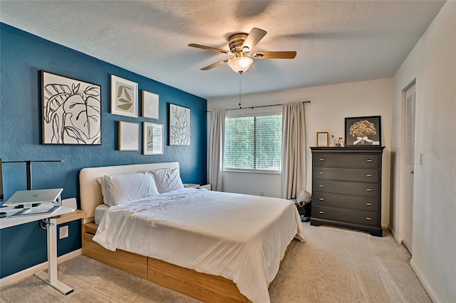 bedroom featuring ceiling fan, a closet, light colored carpet, and a textured ceiling