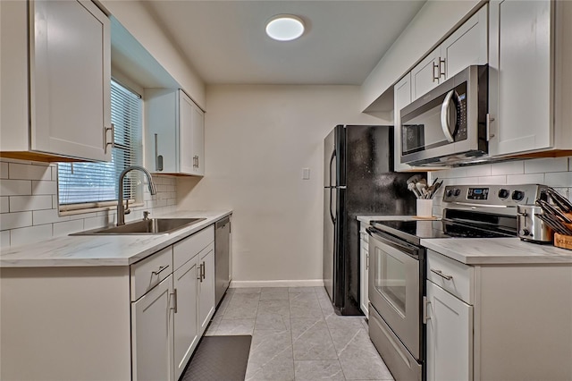 kitchen featuring decorative backsplash, appliances with stainless steel finishes, light stone counters, sink, and white cabinetry