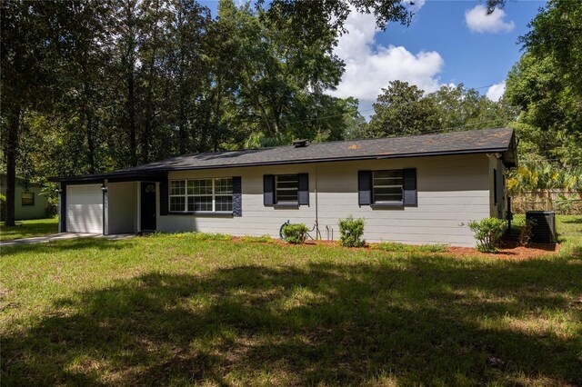 ranch-style house with central air condition unit, a garage, and a front yard