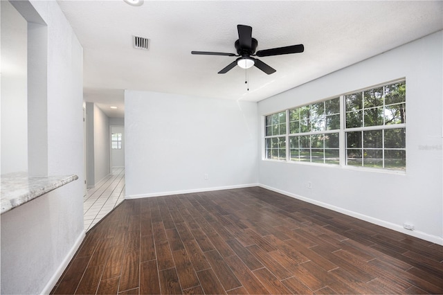 unfurnished room with ceiling fan, plenty of natural light, dark hardwood / wood-style flooring, and a textured ceiling