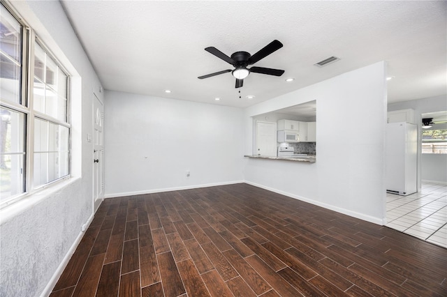 unfurnished living room with a textured ceiling and ceiling fan