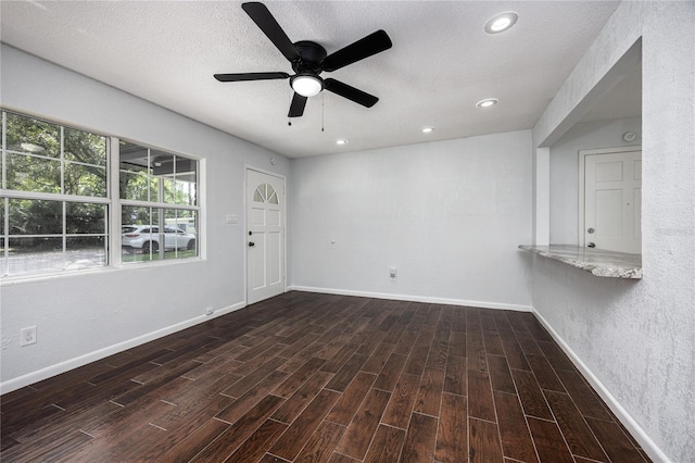 unfurnished room with a textured ceiling, ceiling fan, and dark hardwood / wood-style flooring