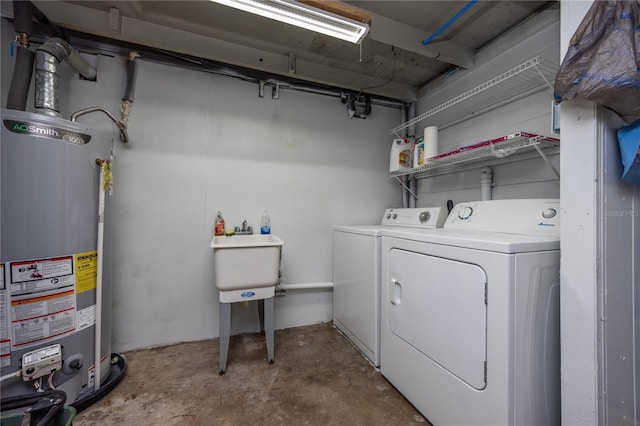 clothes washing area featuring laundry area, water heater, a sink, and washer and clothes dryer