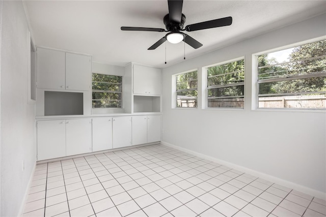 empty room with ceiling fan, plenty of natural light, and light tile patterned flooring