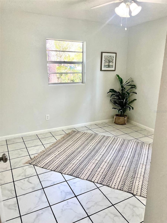 empty room with baseboards, a ceiling fan, and tile patterned floors