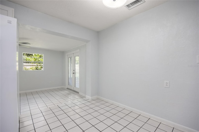 empty room with baseboards, visible vents, french doors, and light tile patterned flooring