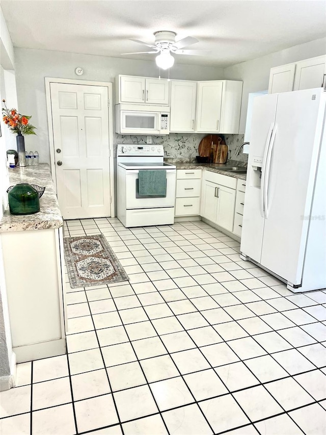 kitchen with tasteful backsplash, light countertops, white cabinets, a sink, and white appliances