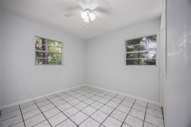 unfurnished room featuring a ceiling fan, a healthy amount of sunlight, and baseboards