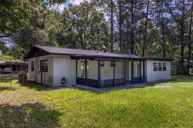 rear view of house with a lawn and fence