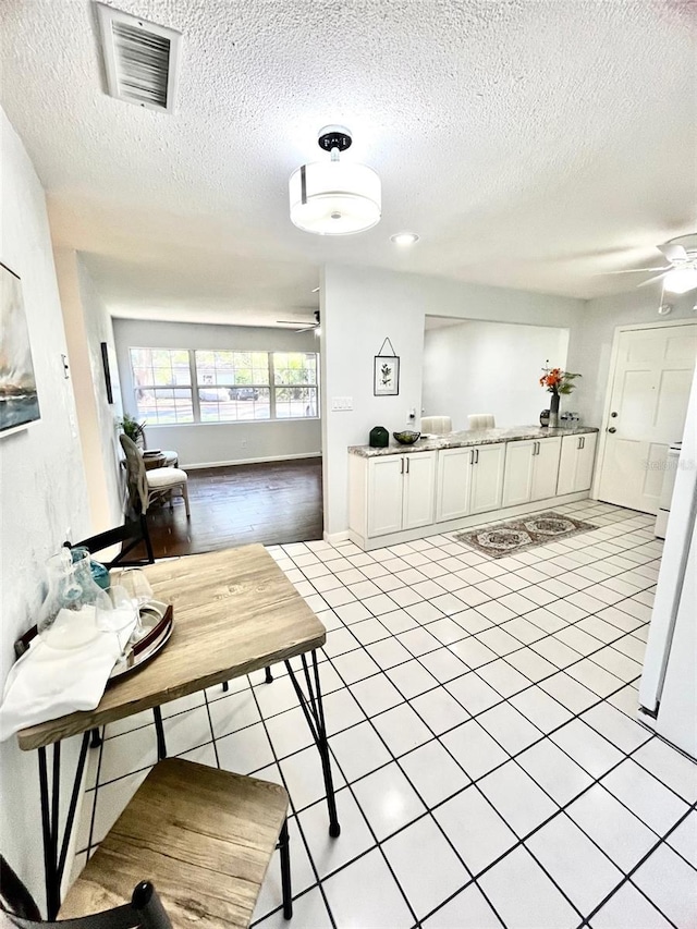 interior space featuring light tile patterned floors, visible vents, and a textured ceiling