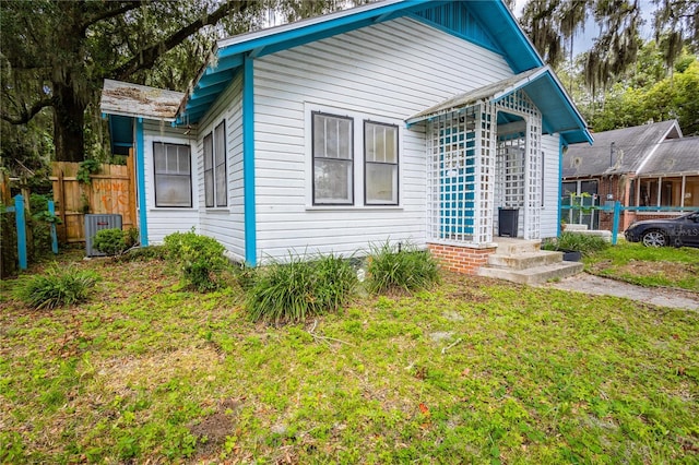 view of front facade featuring a front yard, fence, and central air condition unit