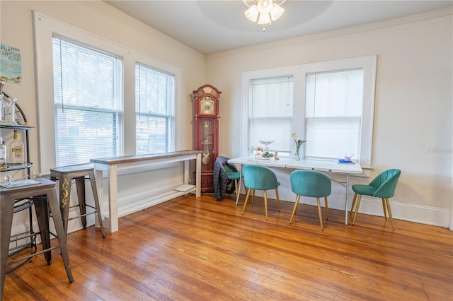 dining room with ornamental molding, breakfast area, wood-type flooring, and baseboards