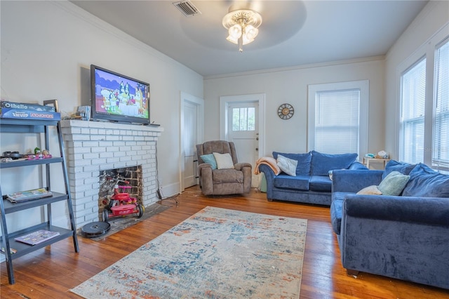 living area featuring a fireplace, visible vents, plenty of natural light, and hardwood / wood-style floors