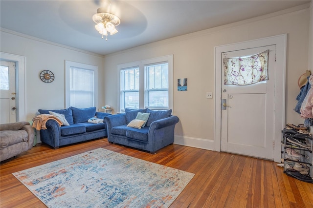 living area featuring ornamental molding, wood-type flooring, a ceiling fan, and baseboards