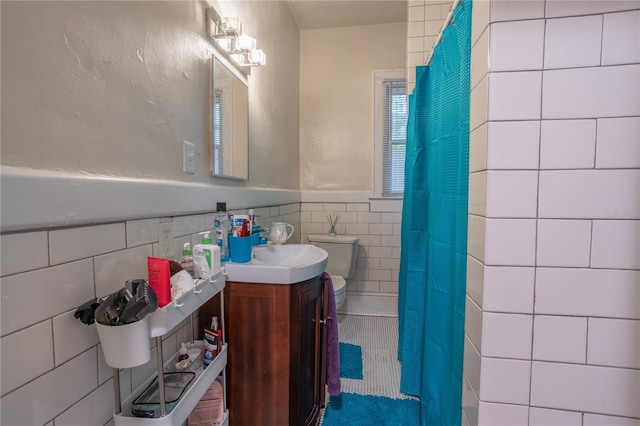 bathroom with vanity, toilet, and tile walls